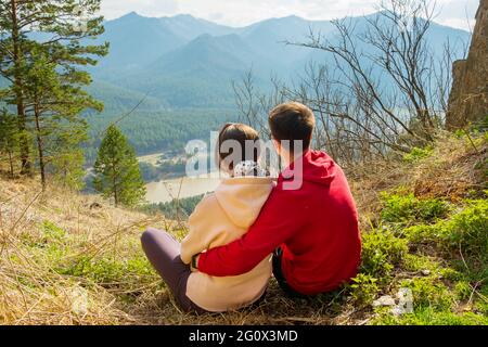 Giovane coppia di viaggiatori che riposa e prende selfie in montagna. Uomo e donna trekking con zaini su un bellissimo sentiero roccioso. Viaggi locali con la famiglia Foto Stock