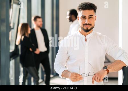Ritratto di bell'uomo d'affari in ufficio e dei suoi colleghi sullo sfondo Foto Stock