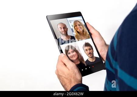 Uomo che ha una videoconferenza di gruppo tramite un tablet. Sfondo bianco. Foto Stock