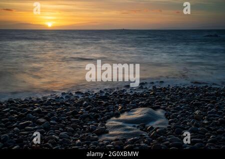 Un colorato tramonto sull'oceano dalla riva di Troon nel Sud Ayrshire, Scozia. Foto Stock