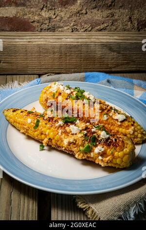 Mais messicano di strada conosciuto anche come elote servito con maionese di peperoncino e formaggio cotija Foto Stock