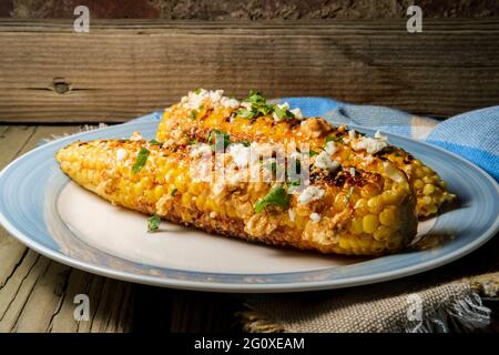 Mais messicano di strada conosciuto anche come elote servito con maionese di peperoncino e formaggio cotija Foto Stock