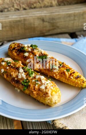 Mais messicano di strada conosciuto anche come elote servito con maionese di peperoncino e formaggio cotija Foto Stock