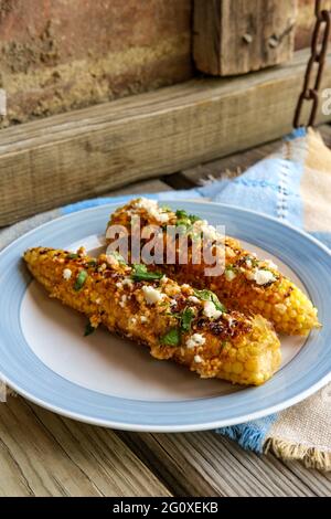 Mais messicano di strada conosciuto anche come elote servito con maionese di peperoncino e formaggio cotija Foto Stock