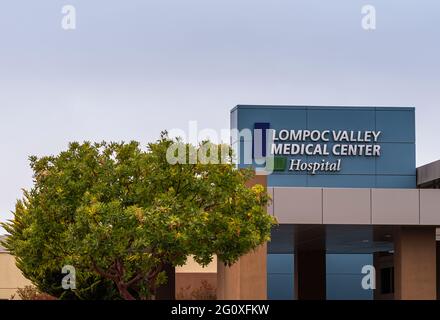 Lompoc, CA, USA - 26 maggio 2021: Emblema bianco su blu del Lompoc Valley Medical Center in cima all'entrata dell'edificio principale sotto il cielo azzurro e lo zelo Foto Stock