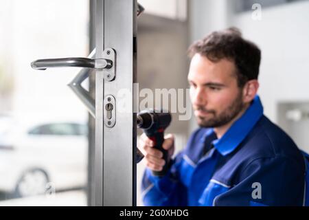 Fabbro uomo riparazione e sostituzione della serratura di metallo della porta Foto Stock