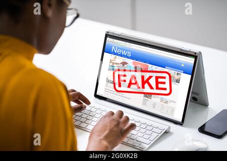 Donna che legge Fake News nel giornale online su laptop Foto Stock