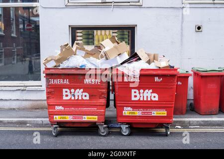 Red Biffa bidoni traboccanti di spazzatura sulla strada. Londra Foto Stock