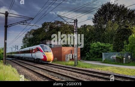 Treno elettrificato Azuma ad alta velocità che passa attraverso un passaggio a livello senza equipaggio auotmatico sulla linea principale della costa orientale. Foto Stock