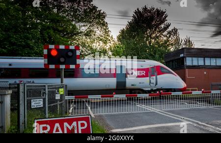 Treno elettrificato Azuma ad alta velocità che passa attraverso un passaggio a livello senza equipaggio auotmatico sulla linea principale della costa orientale. Foto Stock