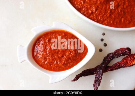 Cibo indiano - pasta di curry di pesce di Goan o masala di base di frutti di cocco rossi. Servito nella ciotola a forma di pesce. Ingredienti sullo sfondo con spazio per la copia. Foto Stock