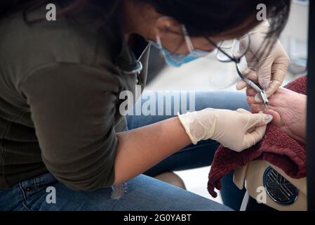 Una donna ispanica di 84 anni che ottiene una combinazione pedicure/manicure al suo salone di bellezza locale. Foto Stock