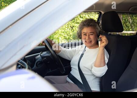 Happy driver donna anziana asiatica mostrando nuove chiavi di auto Foto Stock