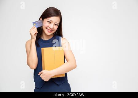 Donna asiatica felice che tiene il pacchetto scatola del pacchetto e carta di credito, servizio di spedizione di consegna e concetto di shopping in linea Foto Stock