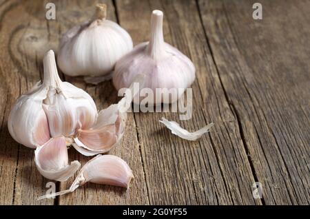 Maturare aglio intero e spicchi sul vecchio tavolo di legno Foto Stock