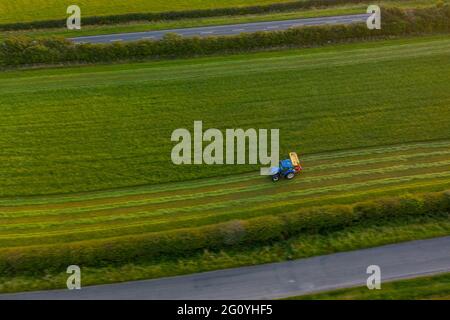 Un agricoltore tende al suo campo in un trattore, mentre un Circus si imposta accanto al Blue Dolphin Holiday Park e il Plough Pub Aerial Images Drone Air Filey Foto Stock