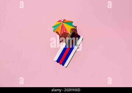 Teli da spiaggia colorati con ombrelloni sulla spiaggia di sabbia rosa. Concetto estivo minimo. Foto Stock