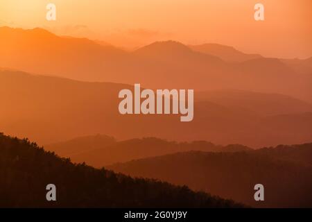 Silhouette arancioni di colline al tramonto durante la tempesta di sabbia Foto Stock