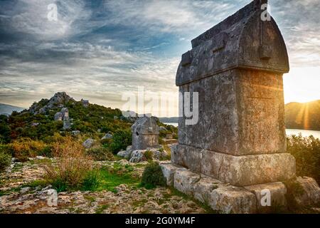 Tombe di pietra intemperie situate sulla collina contro il cielo di tramonto sulla Via Licia in Turchia Foto Stock