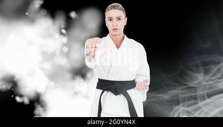 Composizione di combattente di karate caucasico femminile su sfondo nero con sfocatura bianca Foto Stock