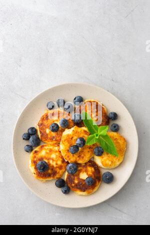 Torta al formaggio Cottage con mirtilli e menta in un piatto su sfondo grigio Foto Stock
