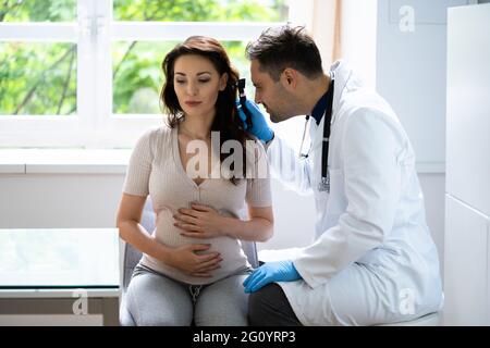 Medico che esamina l'orecchio di un paziente incinta con Otoscopio Foto Stock