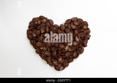 cuore fatto di croccanti fiocchi di mais al cioccolato isolato su sfondo bianco, croccanti fiocchi di cereali al cioccolato per colazione, cibo gustoso Foto Stock