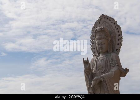 L'enorme statua di Guan yin di fronte al tempio cinese con cielo blu chiaro Foto Stock