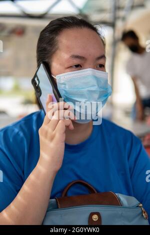Stile di vita locale Asiatico Cinese donne che indossano maschera facciale per proteggerla dall'infezione da Coronavirus mentre attende il cibo al ristorante Foto Stock