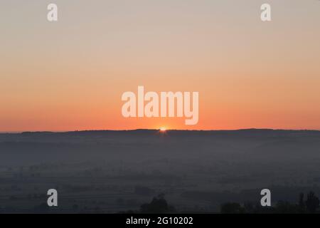 Vista del sole che sorge sui livelli del Somerset da Glastonbury Tor nel Somerset a fine primavera Foto Stock