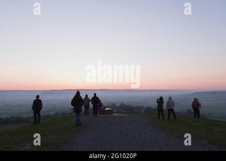 I visitatori di Glastonbury Tor aspettano che il sole salisca all'alba a fine Spring Somerset, Inghilterra Foto Stock