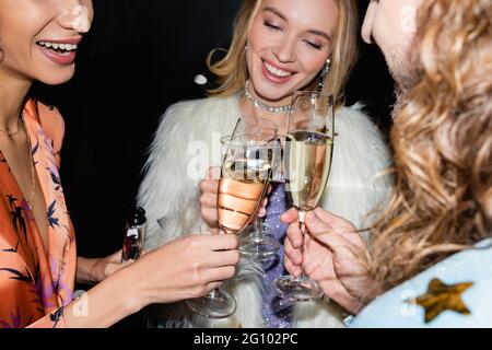 sorridendo giovani amici adulti che bevono nel night club su sfondo nero Foto Stock