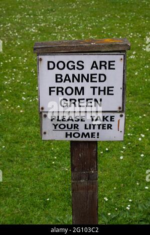 Un segno di legno che dice 'i cani sono vietati dal verde e portare la vostra cucciolata a casa' Foto Stock