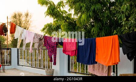 Sul tetto, corda con vestiti puliti all'aperto il giorno di lavanderia. Abiti colorati appesi in abiti. Foto Stock