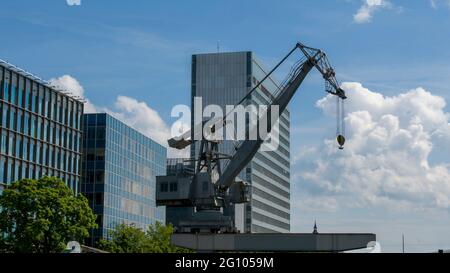 Vecchia gru portuale e moderni edifici aziendali sullo sfondo Foto Stock