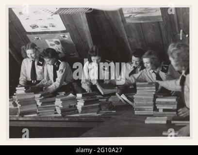 Ragazze dalla tempesta giovanile si impalla; tempesta giovanile. Sei ragazze della tempesta giovanile, in uniforme, sono impegnate ad indirizzare libri per inviare i volontari delle SS olandesi al fronte orientale. Ciò è accaduto attraverso l'organizzazione fondata da Mussert nel 1942. L'imballaggio è accaduto in un attico, appendere foto o disegni di aerei sulla parete. Foto Stock