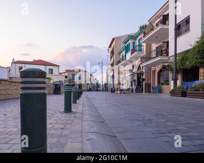 Pavimentazione in pietra con pali anti-parcheggio lungo il marciapiede nel centro della città vecchia di Larnaca con un colorato cielo di tramonto serale a Cipro. Foto Stock