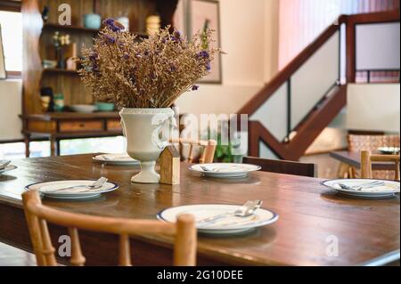 Antico tavolo da pranzo in legno con stoviglie e vaso di fiori nel ristorante Foto Stock