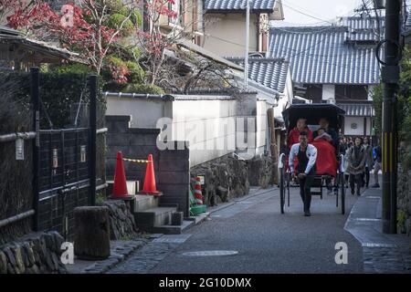 KYOTO, GIAPPONE - 11 Dic 2019: Kyoto, Giappone-26 Nov, 2019: Il pilota di risciò con i suoi clienti guida sulla strada ad Arashiyama, Kyoto Foto Stock