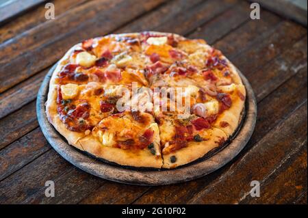 Pizza al barbecue con pancetta hawaiana affumicata fatta in casa su vassoio di legno Foto Stock