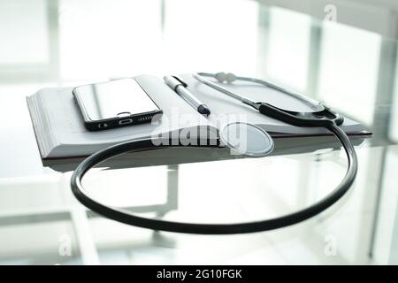 Telefono diario penna e stetoscopio su tavolo di vetro Foto Stock