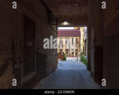 Si attraversa l'antico edificio in mattoni a due piani in rovina, con vista su un edificio in mattoni forsaken a metà piano nel centro della città di Kiev. Foto Stock