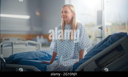 Modern Hospital Ward: Bella paziente caucasico femminile che riposa su un letto, completamente in recupero dopo un intervento chirurgico riuscito, malattia o Coronavirus lei Foto Stock