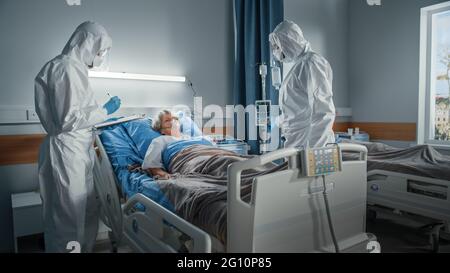 Hospital Coronavirus Emergency Department Ward: Medici, paramedici indossare tute, maschere viso salvare la vita di un paziente femminile anziano sdraiato nel letto Foto Stock