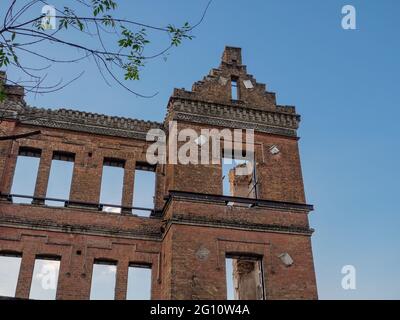 Pareti esterne in mattoni rossi di un antico edificio semi-rovinato con un bel pezzo di intonaco. Concetto di ricostruzione. Foto Stock