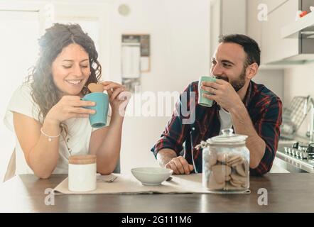 Giovane coppia millenaria che si diverte in cucina - coppia amorosa che fanno colazione insieme nella loro nuova casa - filtro caldo sullo sfondo Foto Stock