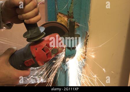 Lavoratore il taglio di metallo con la fresa. Scintille volanti durante la macinazione di ferro Foto Stock