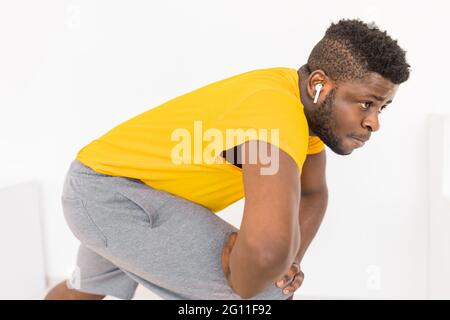 L'uomo afroamericano sportivo che fa gli esercizi di affondo per l'allenamento muscolare delle gambe a casa da solo. Attivo concentrato nero maschio facendo avanti Foto Stock