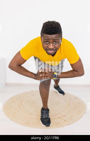 Profilo ritratto di afroamericano sportivo maschile in giallo brillante sportswear in piedi su tappeto tappeto a casa, guardando la fotocamera, praticando sport, lavoro Foto Stock