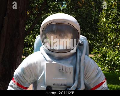 Scultura di un astronauta sullo sfondo di alberi verdi nel parco in giornata di sole. Foto di primo piano Foto Stock